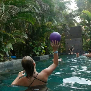 Girls are playing with the ball in the pool at the hostel