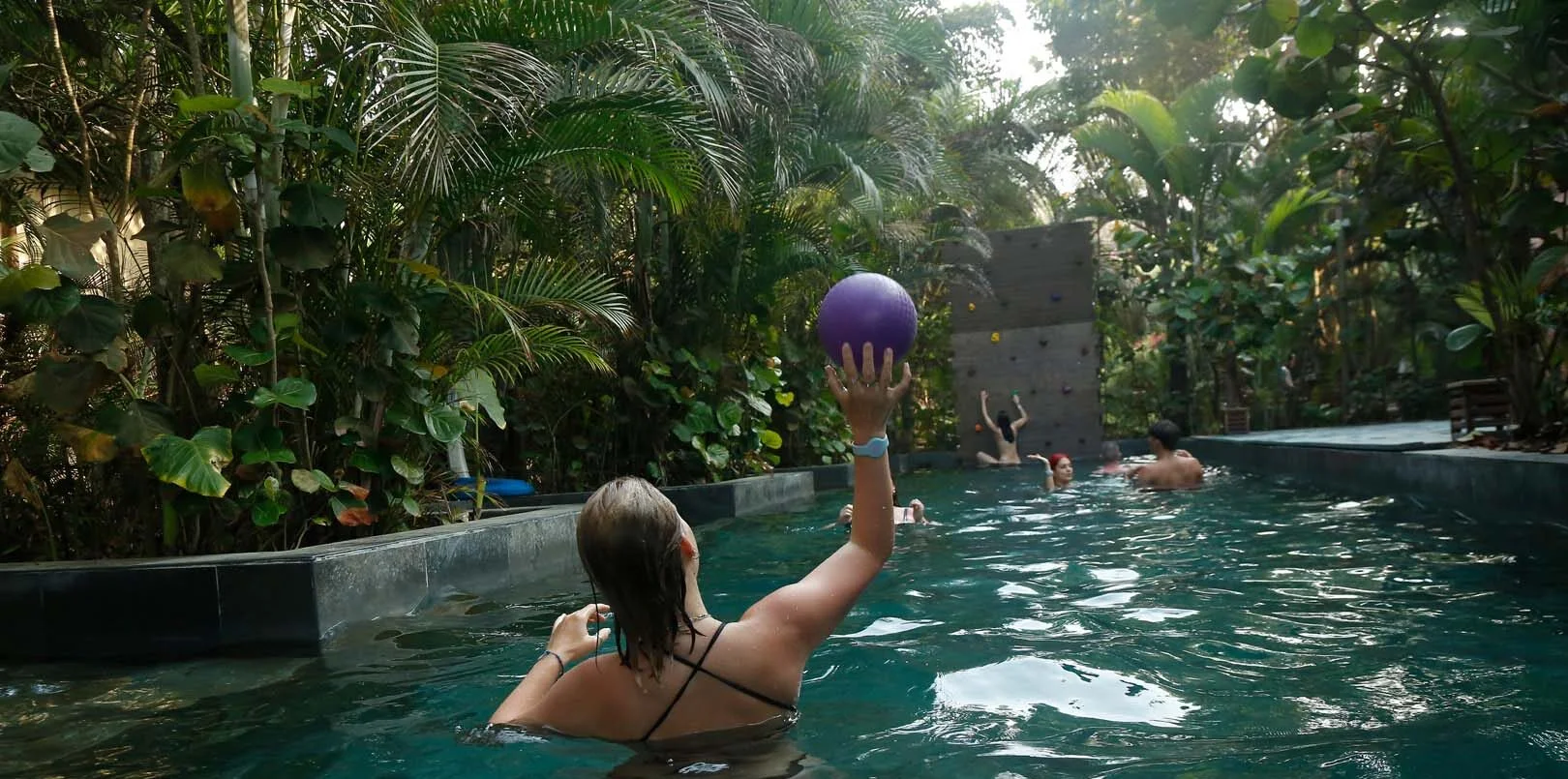 Girls are playing with the ball in the pool at the hostel